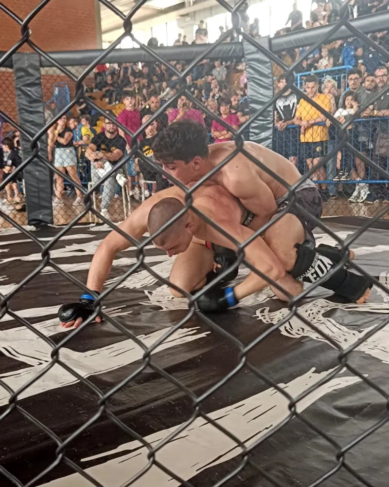 Atleti impegnati in un incontro di MMA in gabbia davanti al pubblico