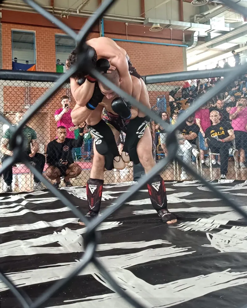 Atleti di MMA in gabbia durante un incontro davanti agli spettatori